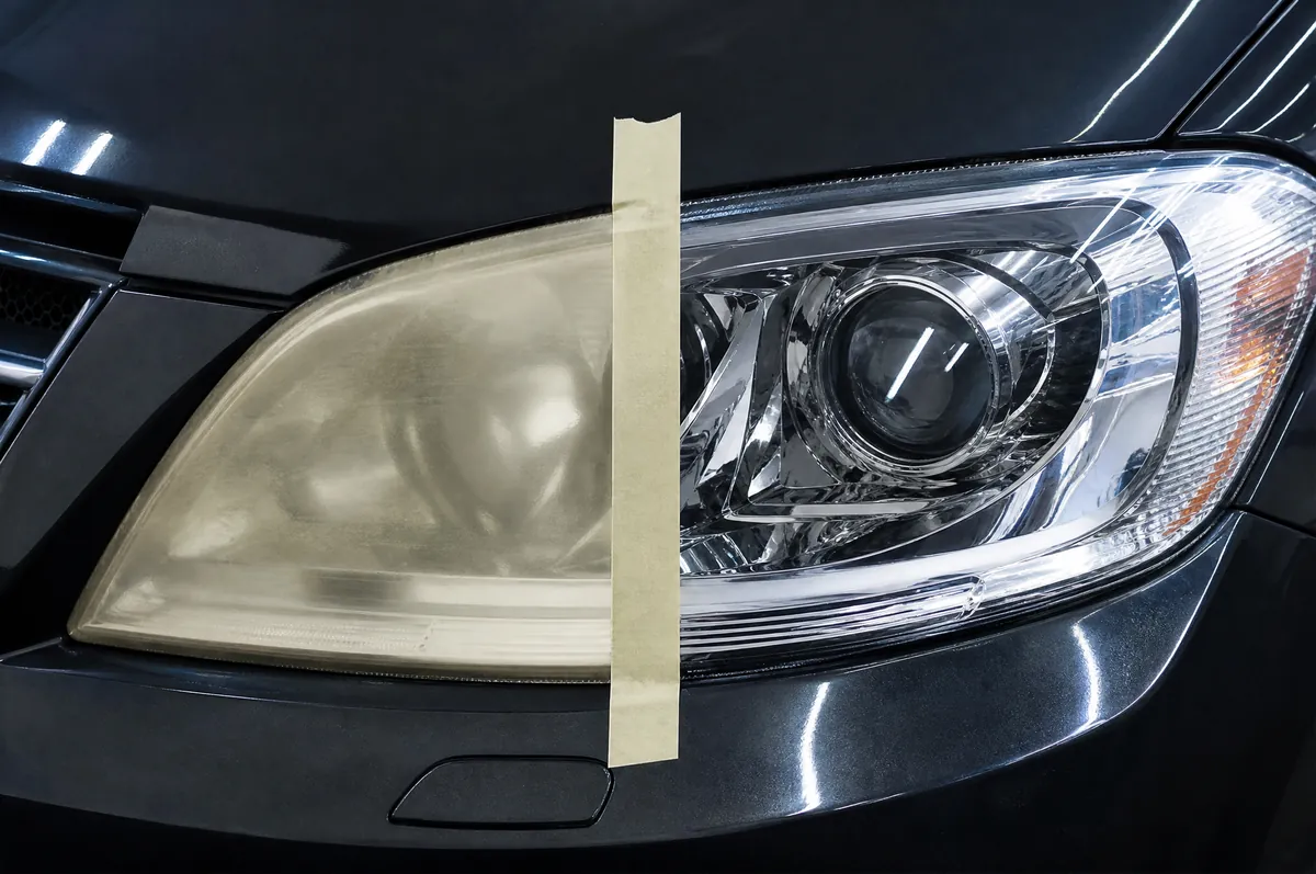 A headlight taped down the middle, one half yellowed and hazy, the other half restored to clear